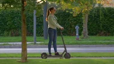 Gülümseyen kadın banliyölerde yenilikçi bir e-scooter sürüyor.