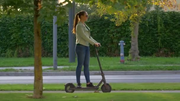 SLOW MOTION : Une femme souriante conduit un scooter électrique innovant à travers les banlieues — Video