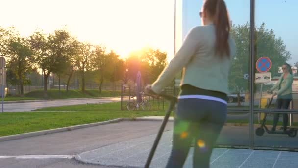 SUN FLARE Rayons de soleil dorés brillent sur la femme équitation e scooter autour du bâtiment vitreux — Video