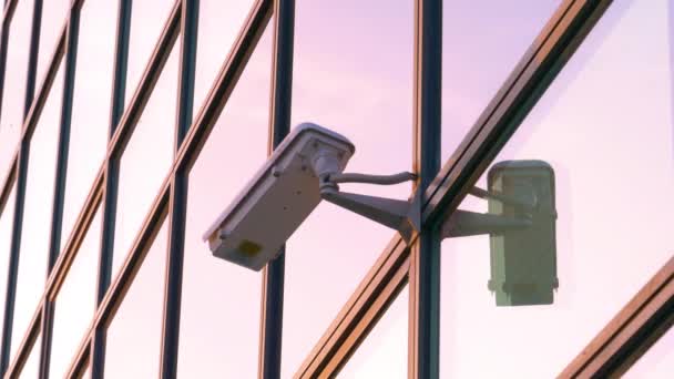CLOSE UP: CCTV camera surveils the street near a modern building at sunset. — Stock Video