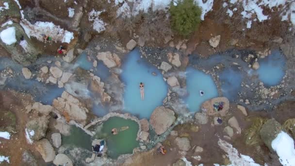 DRONE Πεζοπόροι κάνουν ένα θεραπευτικό μπάνιο σε θερμές τυρκουάζ πισίνες στο χειμερινό τοπίο — Αρχείο Βίντεο