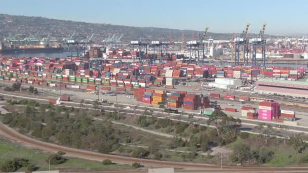 DRONE: Auto e camion guidano lungo l'autostrada passando davanti al colorato porto di LA — Video Stock