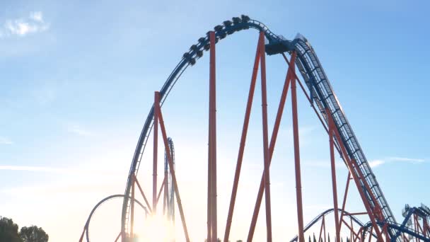 LENS FLARE: Golden sunbeams shine on the massive loop of a roller coaster ride — Stock Video