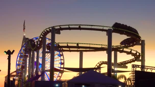 SILHOUETTE: Bela vista do parque de diversões no cais de Santa Monica ao pôr-do-sol. — Vídeo de Stock