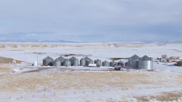 DRONE: Volare intorno a grandi silos di stoccaggio in acciaio nelle pianure innevate del Montana. — Video Stock