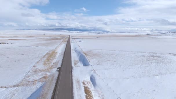 Flyger längs en lång rak väg som leder genom den vintriga Montana — Stockvideo