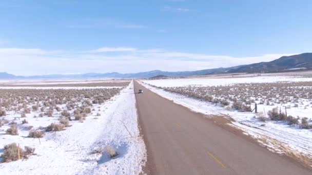AERIAL: Turistas en un divertido viaje de invierno por carretera a lo largo de la carretera escénica en Montana — Vídeos de Stock