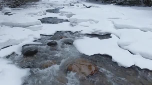 CLOSE UP: Forest stream splashes while making its way through snowy landscape. — Stock Video