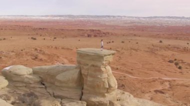 Kum taşı oluşumundan kanyonu gözlemleyen genç bir kadının etrafında uçmak.