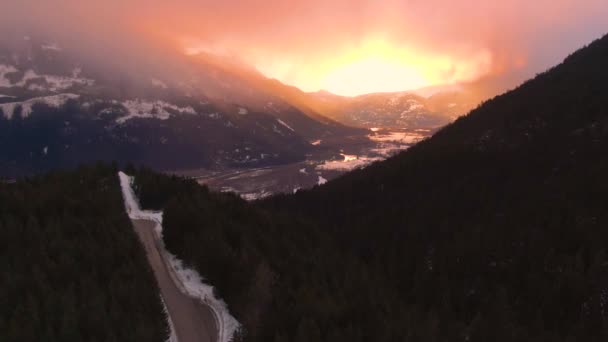 AERIAL: Vliegen langs schilderachtige snelweg die door het bos bij zonsopgang. — Stockvideo