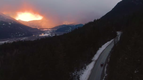 AERIAL: Zimowy poranek niebo rozciąga się nad samochodem jadąc przez las w Kanadzie. — Wideo stockowe