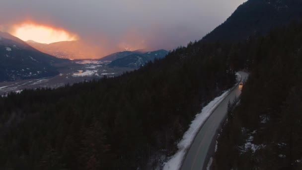 DRONE: Carro dirige ao longo da estrada cruzando os pinheiros em nevado Canadá. — Vídeo de Stock