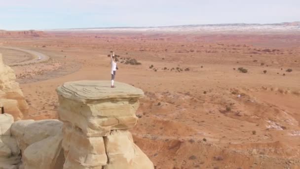 Spannende vrouwelijke reiziger die bovenop een rots met uitzicht op de canyon staat — Stockvideo