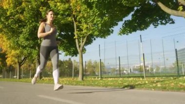 Genç bir bayan koşucunun canlı yürüyüş yolunda koşarken çekilmiş sinematik bir çekimi.