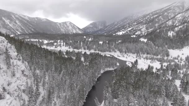 AERIAL: Spectaculair uitzicht vanuit de lucht op een meanderende rivier dwars door de besneeuwde vallei. — Stockvideo