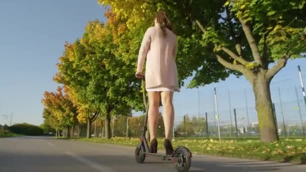 LOW ANGLE: nierozpoznana młoda kobieta w wysokich obcasach jeździ na skuterze elektrycznym do pracy. — Wideo stockowe