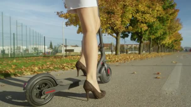 Близко: Неузнаваемая женщина на высоких каблуках начинает ездить на электрическом скутере . — стоковое видео