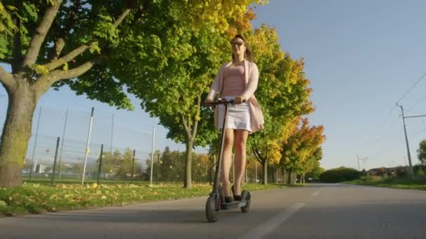 FAIBLE ANGLE : Millennial manèges e-scooter sur la route en cours d'exécution après l'automne arbres colorés. — Video