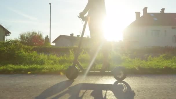 LOW ANGLE: Urban flicka i klackar rider elektrisk skoter på en solig höstmorgon. — Stockvideo