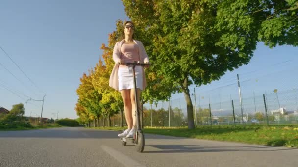 LOW Kąt: Młoda kobieta rejsy wzdłuż jesiennej drogi kolorowe w słoneczne popołudnie. — Wideo stockowe