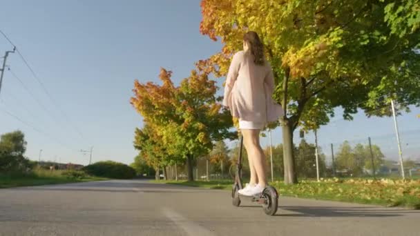 COPY SPACE: Onherkenbare jonge vrouw rijdt langs de laan op een elektrische scooter — Stockvideo