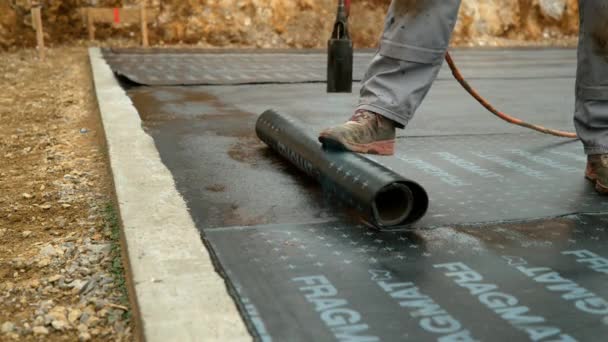 FERMETURE : L'entrepreneur brûle un rouleau noir de papier goudron sur une fondation en béton. — Video