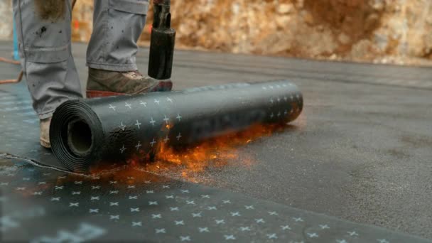 ZAMKNIJ Laborer topi rolkę smoły na fundament budowanego domu — Wideo stockowe