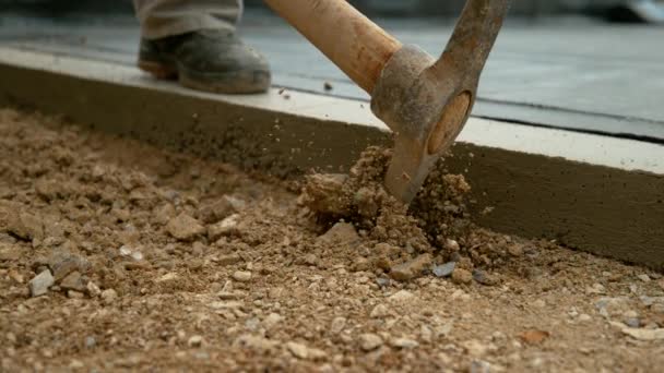 FECHAR UP: Trabalhador irreconhecível usa picareta para começar a cavar no chão de cascalho — Vídeo de Stock