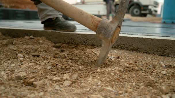 CHIUSURA, DOF: Piccone di metallo colpisce nel terreno morbido mescolato con ghiaia. — Video Stock