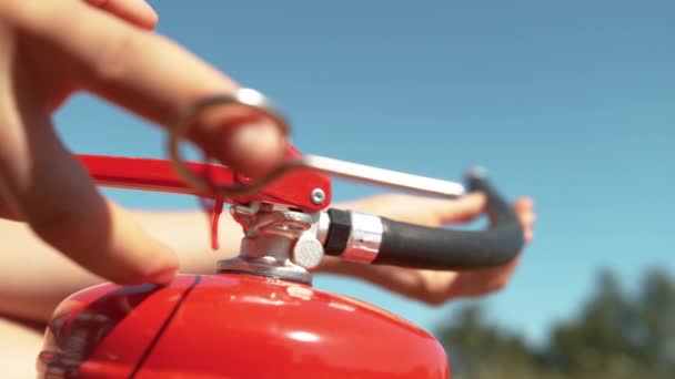 Jonge vrouw trekt een veiligheidsspeld uit een brandblusser voordat ze hem gebruikt. — Stockvideo