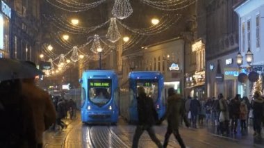Zagreb 'de soğuk bir kış gecesinde tramvaylar neşeli bir caddeden geçiyor.