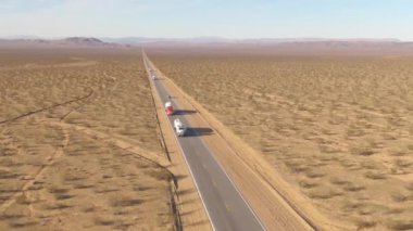 Nakliye kamyonları, Mojave Çölü 'nden geçen boş otoyoldan kargo taşıyor..