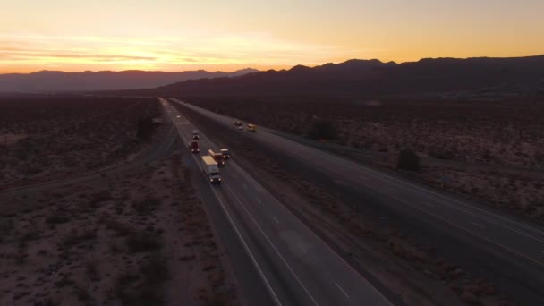 AERIAL: Lastbilar och bilar kör nedför motorvägen Mojave en solig kväll. — Stockvideo