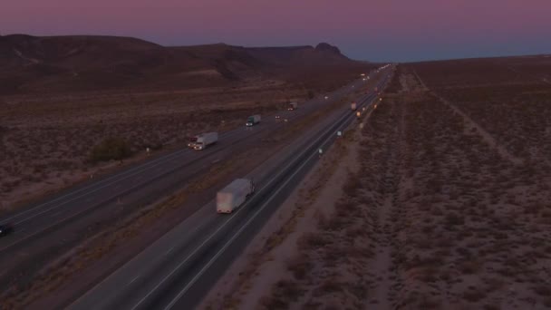 AERIAL: Voando atrás de um caminhão de carga transportando carga através do deserto de Mojave de madrugada — Vídeo de Stock