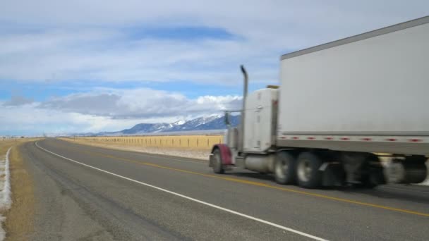 Roter LKW transportiert an kalten Wintertagen Fracht durch die malerische Wildnis von Montana. — Stockvideo