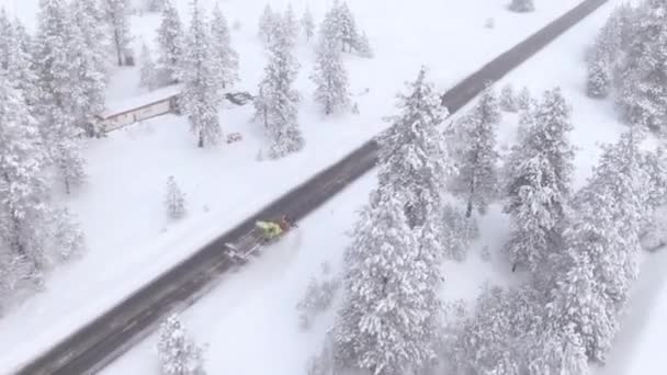 AÉRIAL : Camion de labour de neige nettoie la route de campagne menant à travers la forêt. — Video