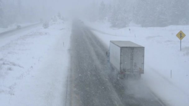 Lastwagen und Autos bahnen sich ihren Weg durch einen Schneesturm auf einer gefährlichen Landstraße — Stockvideo