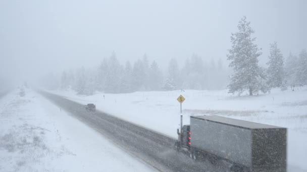 Semi-camiones y coches conducen a lo largo de una carretera nevada en condiciones climáticas horribles . — Vídeo de stock