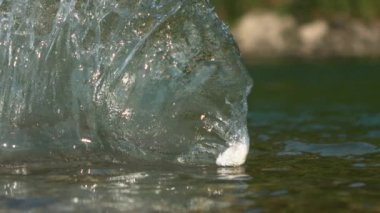 Beyaz çakıl taşı bir dağ deresinin sakin yüzeyinde süzülür..