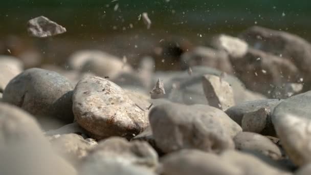 MACRO: Pedra quebra e despedaça em pedaços depois de cair na margem do rio . — Vídeo de Stock