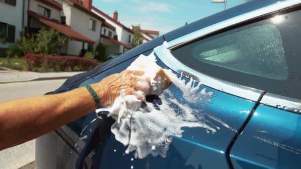 GESCHLOSSEN: Unbekannter fährt seifigen Schwamm an blauem Auto entlang. — Stockvideo