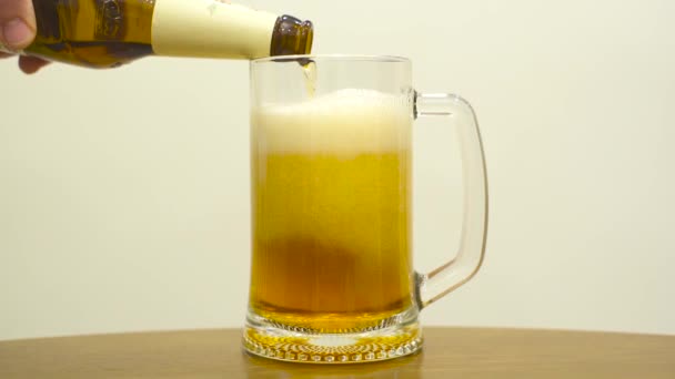 Verser de la bière dans un verre sur fond blanc. Mouvement lent 