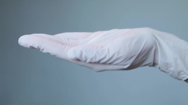 Mujer en guantes médicos poner píldoras ovaladas blancas en la mano — Vídeos de Stock