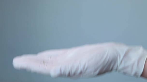 Женщина в медицинских перчатках положить желтые овальные таблетки в руку — стоковое видео