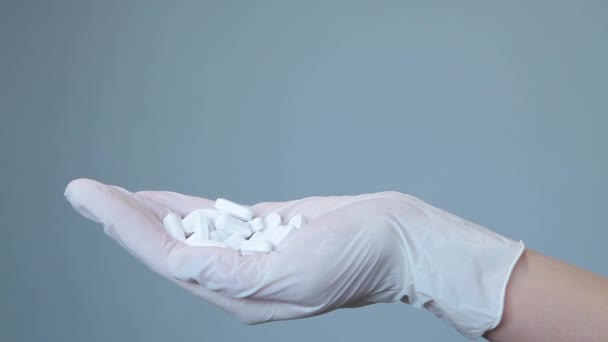Frau in Arzthandschuhen nimmt weiße ovale Pillen — Stockvideo