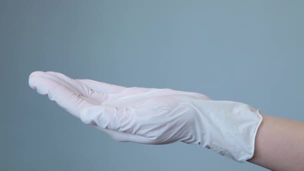 Mujer en guantes médicos poner píldoras redondas blancas en la mano — Vídeo de stock