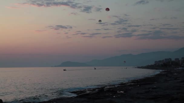 Парасейлінг на заході сонця. парашут літає за човном — стокове відео
