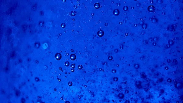Blue shiny relaxing bubbles in a sticky liquid, abstract concept.