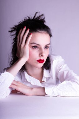 Dudaklarında kırmızı ruj lekesi olan beyaz arka planda beyaz gömlekli güzel bir genç kız.