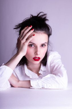 Dudaklarında kırmızı ruj lekesi olan beyaz arka planda beyaz gömlekli güzel bir genç kız.